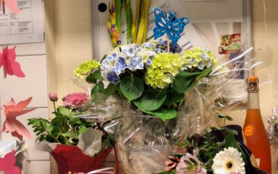 Farbenfroher Arbeitsplatz übersät mit Blumensträußen, Geschenken und Dekorationen