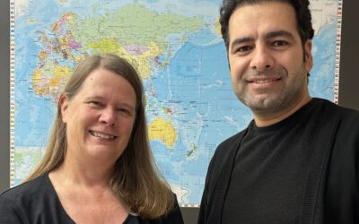Stefanie Ludwig und Ebrahim vor einer Weltkarte im Asklepios Willkommenszentrum Hamburg