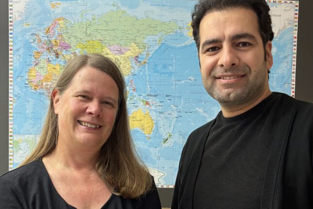 Stefanie Ludwig und Ebrahim vor einer Weltkarte im Asklepios Willkommenszentrum Hamburg